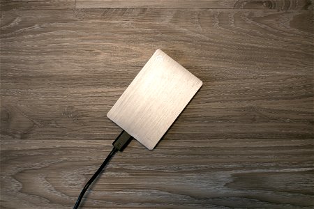 Plugged Silver External Hard Drive On Wooden Surface photo