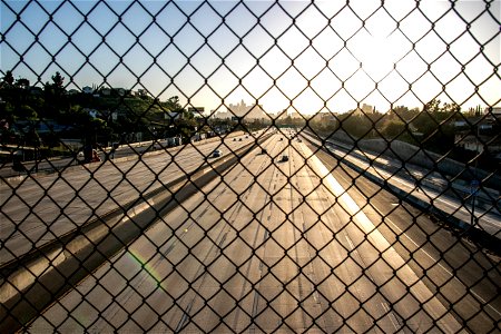 Sun Beyond Highway Behind Chain Link Fence photo