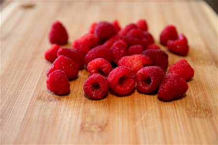 Close Up Of Raspberries On Wooden Cutting Board