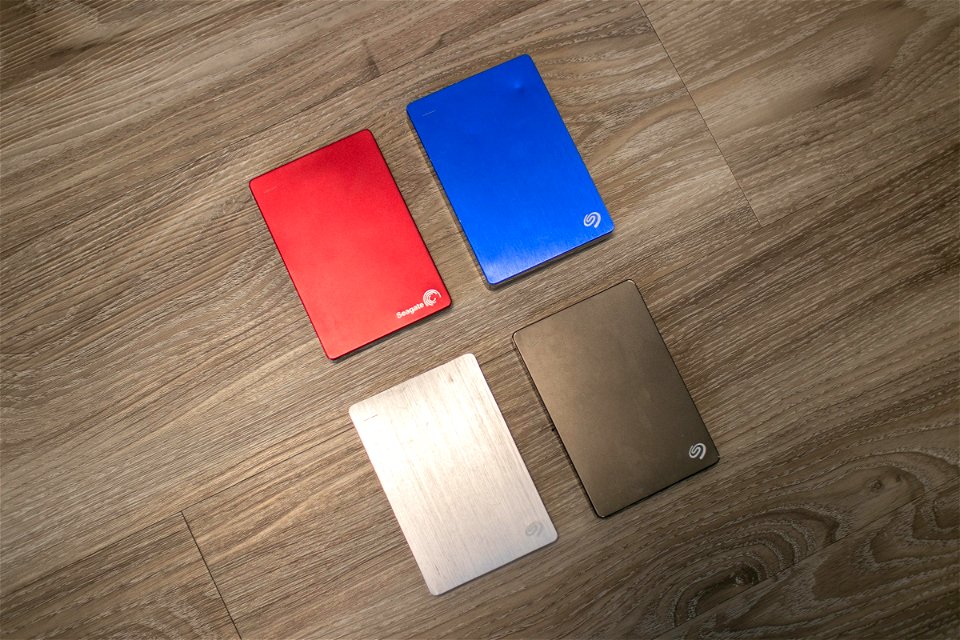 Four External Hard Drives On Wooden Surface