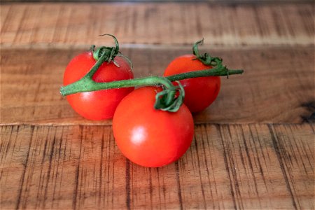Three Tomatoes On Wooden Surface photo