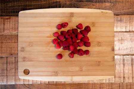Handful Of Raspberries On Wooden Cutting Board photo