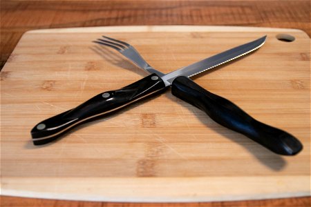 Steak Knife And Fork On Wooden Cutting Board photo