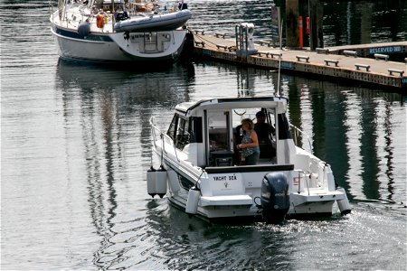 Two People On Small Yacht Near Pier photo