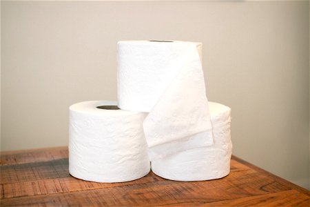 Three Stacked Toilet Paper Rolls On Wooden Table photo