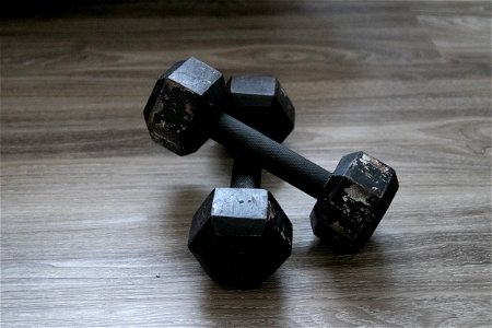 Pair Of Scratched Black Dumbbells On Wooden Surface