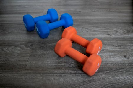 Two Pairs Of Dumbbells On Wooden Surface photo