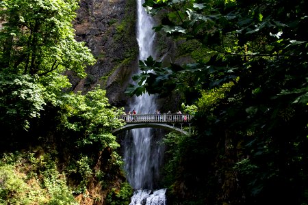 Mountain Waterfall Behind Arch Bridge In Forest photo