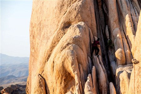 Man Climbing Rock Formation In Joshua Tree Park photo