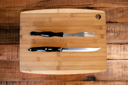 Fork And Knife On Wooden Cutting Board photo