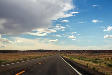 Empty Highway In Desert Under Cloudy Blue Sky