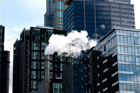 White Smoke From Chimney Surrounded By Tall Buildings photo