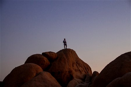 Man On Top Of Big Rock During Twilight