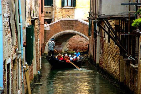 Tourists On Gondola In Canal Near Bridge