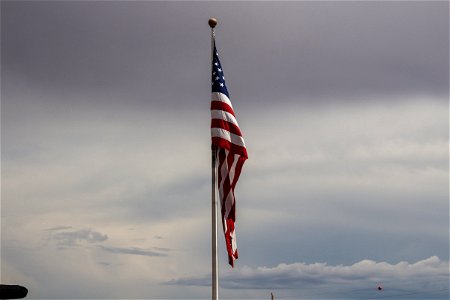 Motionless American Flag On Pole Against Gray Sky