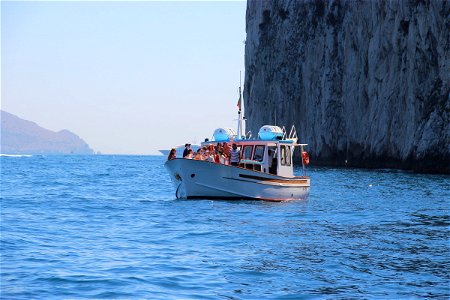 People On Boat In Water Near Cliff photo