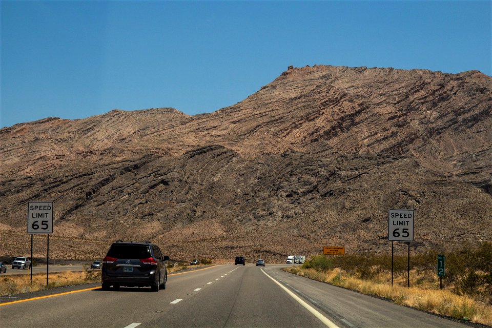 Cars In Road Towards Mountains