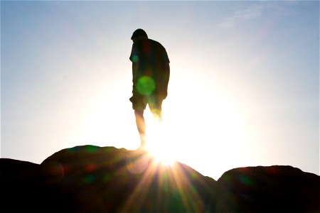 Sunrays Through Man’s Legs On Rock photo