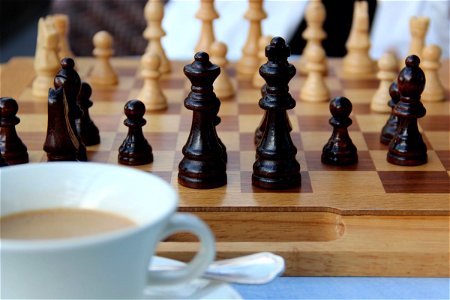 Chess Pieces On Board With Coffee Cup photo