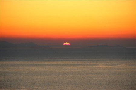 Sunset Behind Hill In Ocean photo
