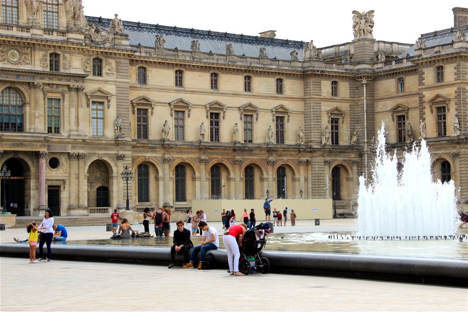 People Sitting By Water Fountain In Courtyard photo