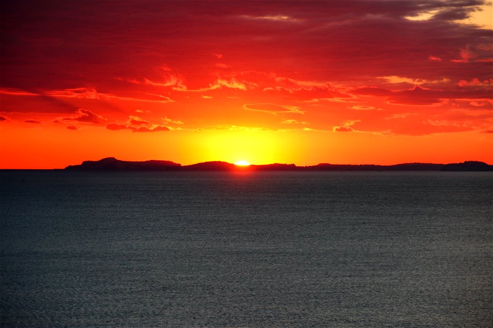 Sunset Behind Island In Ocean photo