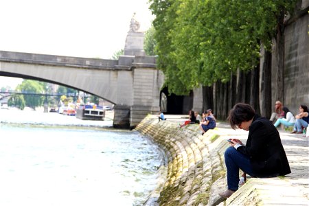 Man on Phone Sitting by River Bank photo