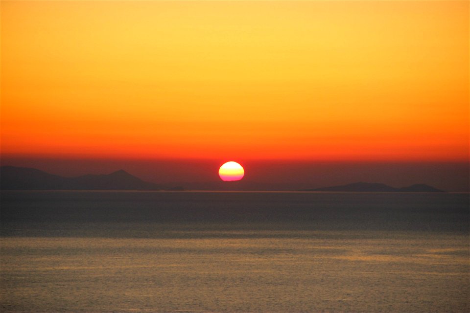 Sunset Behind Land on Ocean photo