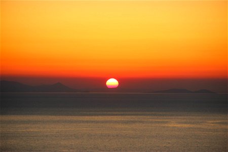 Sunset Behind Land on Ocean photo