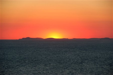 Sunset Behind Island in Ocean photo
