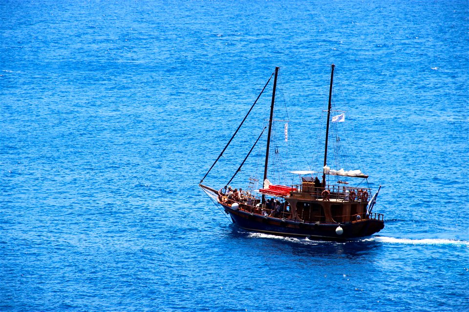 People in Old Sailboat in Ocean photo