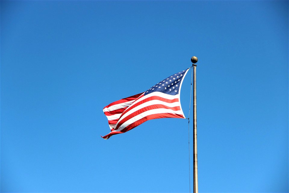 American Flag Waving on Pole in Blue Sky