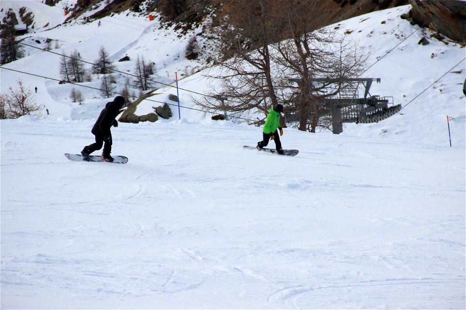2 People Snowboarding Down Hill