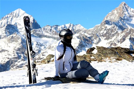 Woman Sitting Next to Skis in Mountains photo