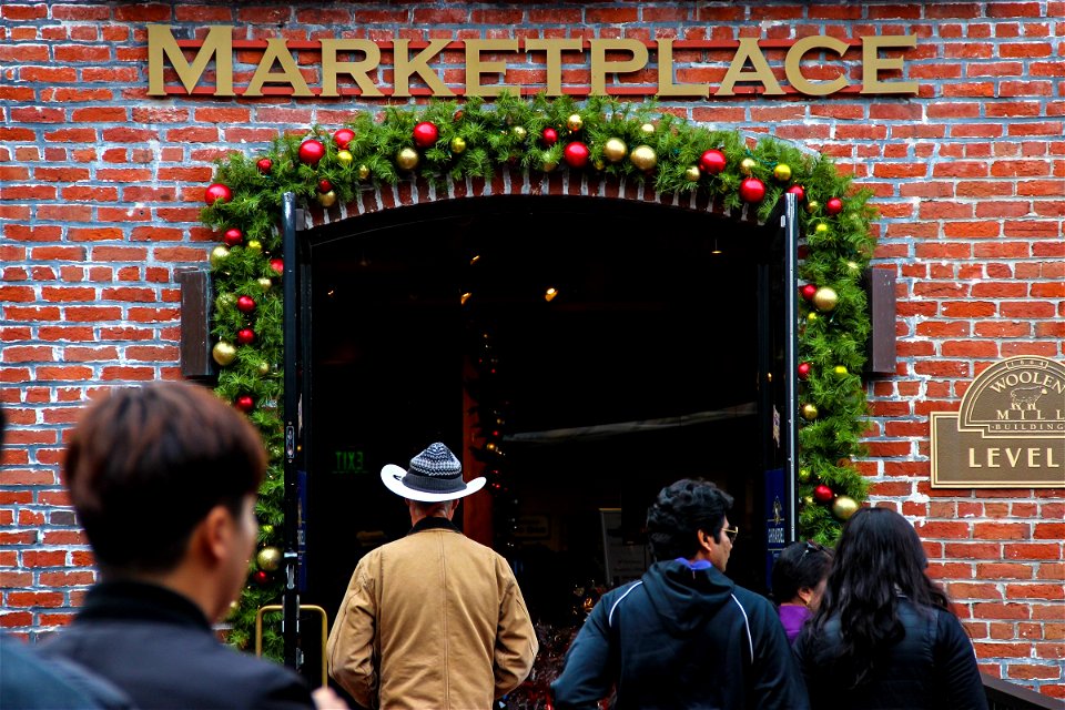 People Walking into Christmas Decorated Marketplace Building