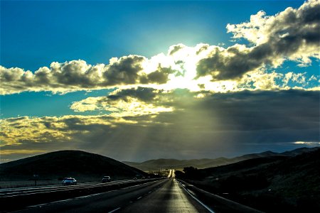 Sun Shining Through Clouds on Highway photo