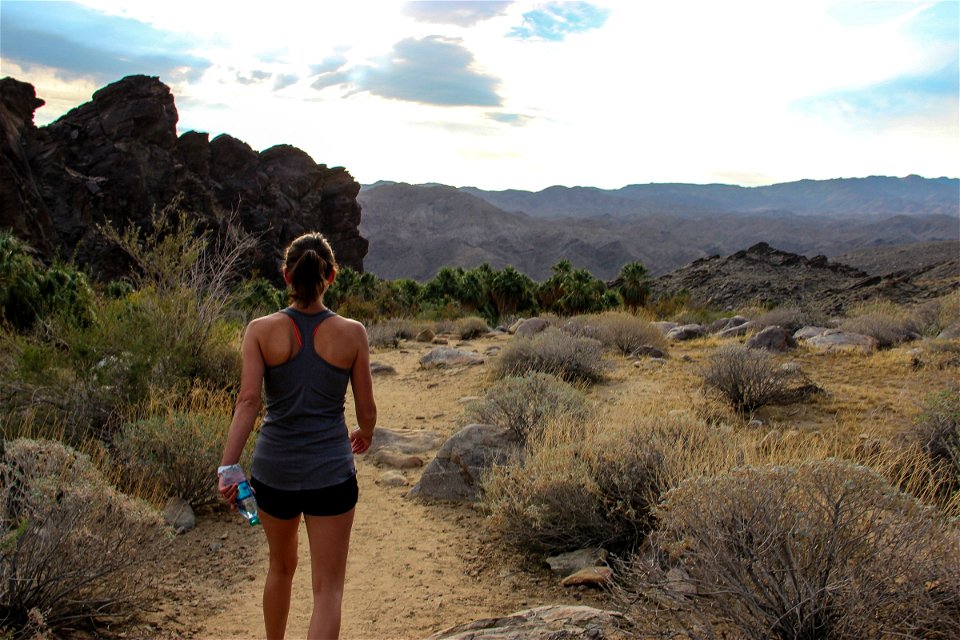 Woman with Water Bottle Walking Through Desert photo