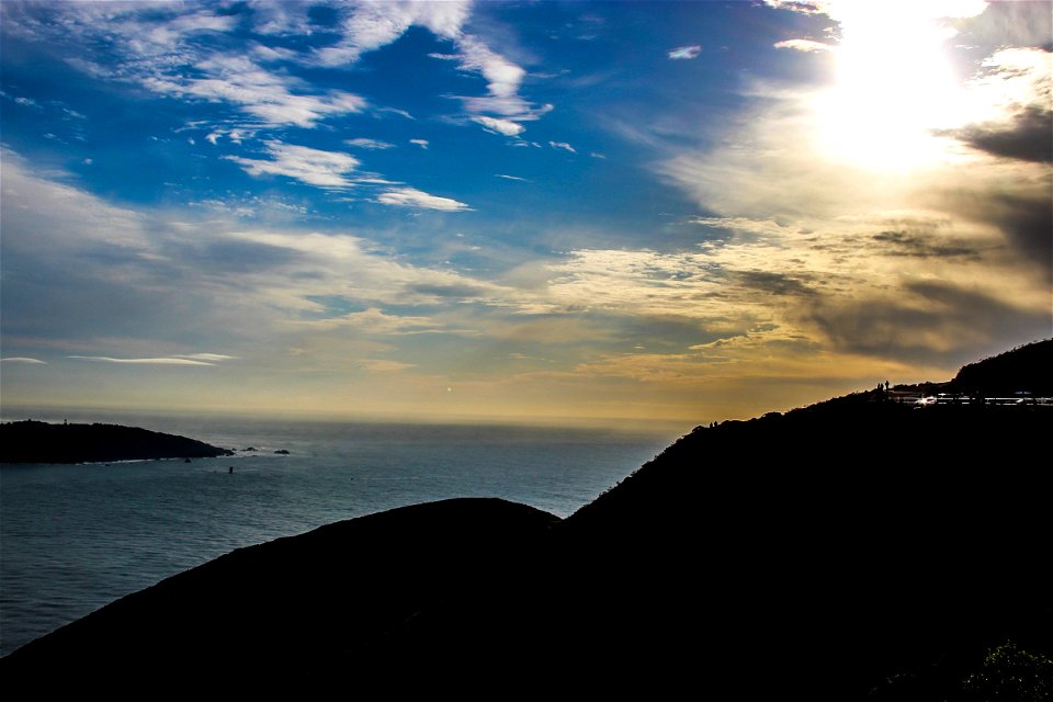 Silhouette of Hill by Ocean Under Sun