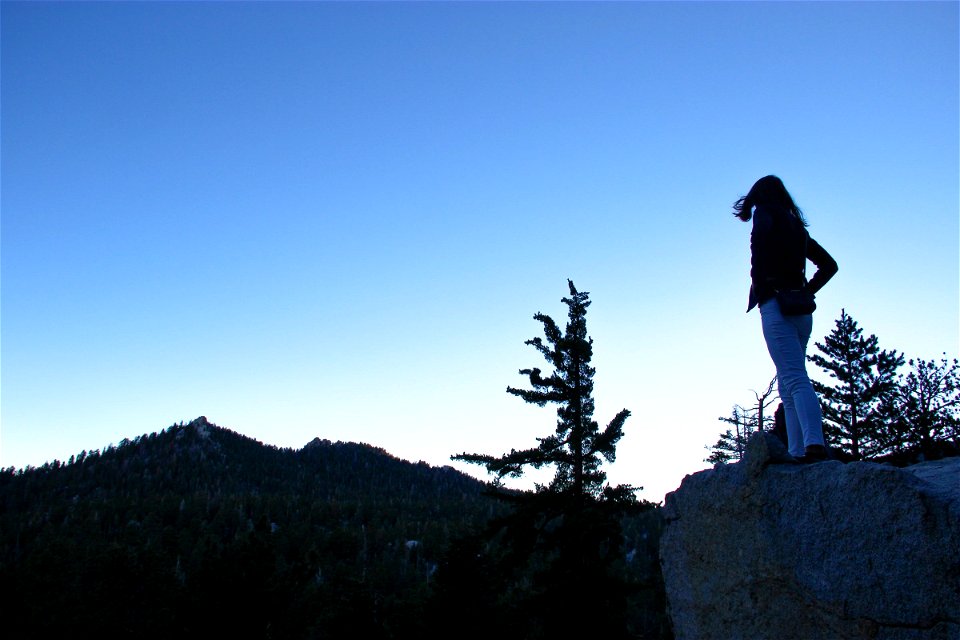 Silhouette of Woman Standing on Rock in Mountains photo