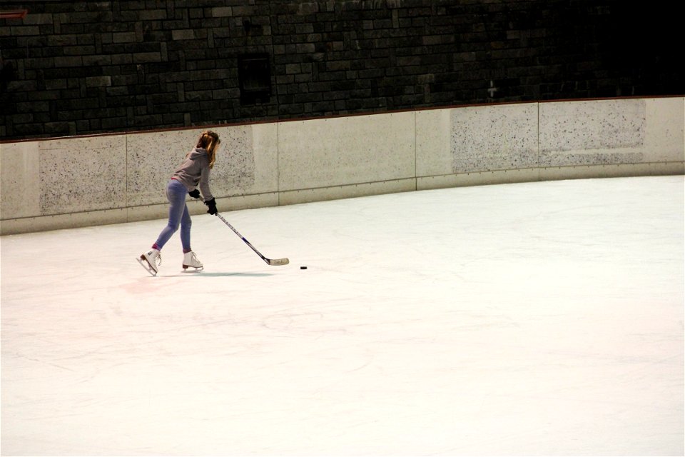 Girl Skating on Ice with Hockey Stick