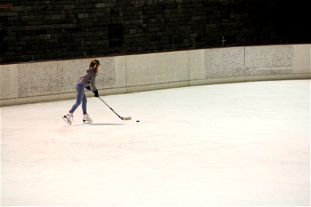 Girl Skating on Ice with Hockey Stick