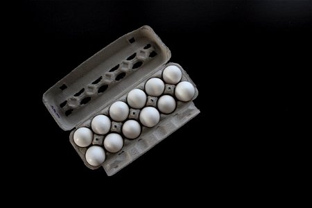 Dozen Eggs in Carton on Dark Table photo
