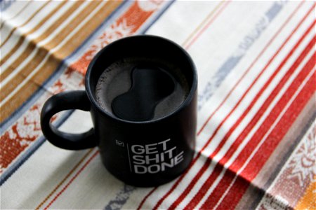 Coffee in Black Mug on Colorful Tablecloth photo
