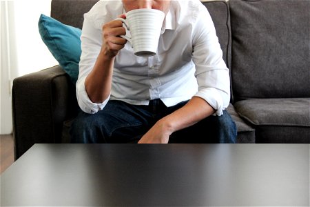 Man on Couch Drinking from Mug photo
