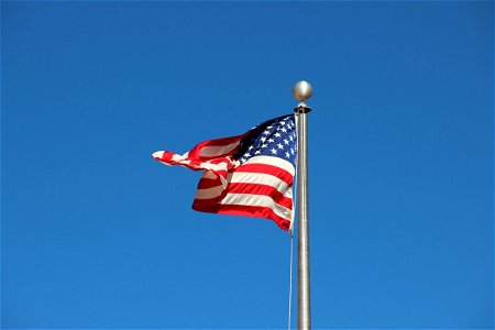 American Flag Waving on Pole in Blue Sky photo