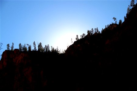 Sun Behind Cliff with Trees photo