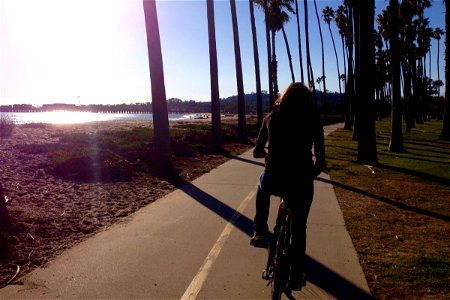 Woman Riding Bicycle on Path Along Beach photo