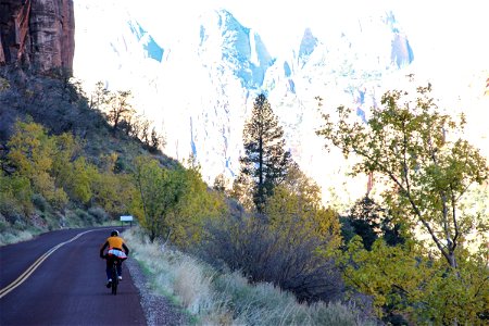 Man Riding on Bicycle Alongside Mountains photo