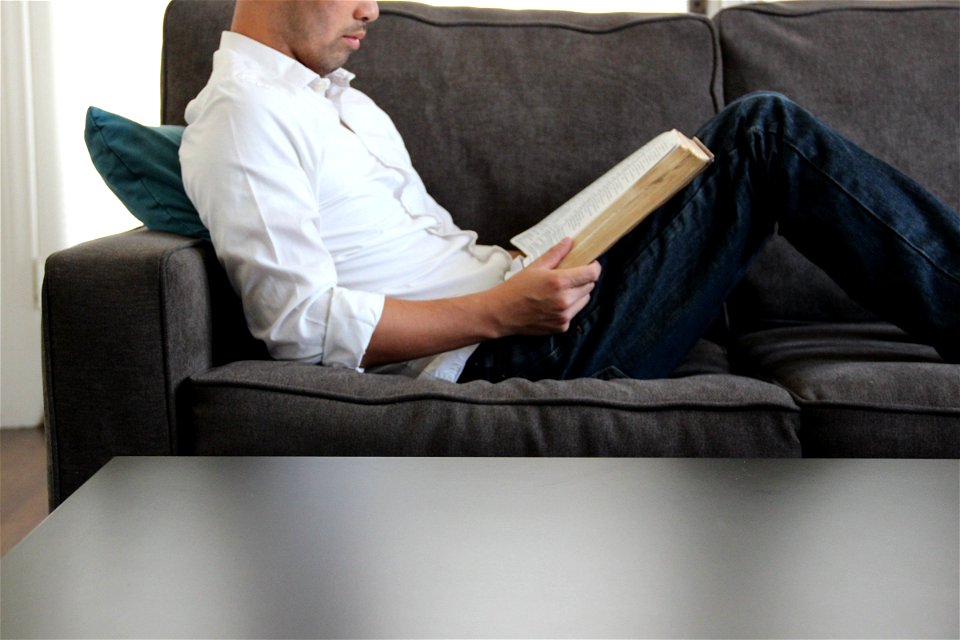 Man Sitting on Couch Reading Bible