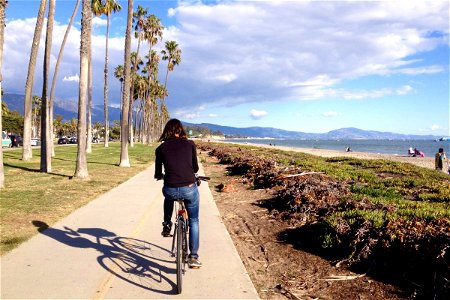 Woman Riding Bicycle on Path Along Beach photo